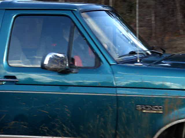 Side view of a teal 1996 Ford Bronco with a chrome side mirror