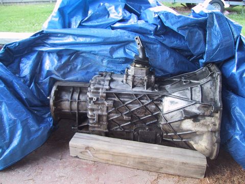 1994 Ford Bronco - A removed ZF manual transmission with cast aluminum ribbed case, bellhousing, shifter tower and stub shift lever, propped on a wood block o…