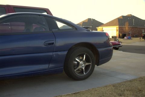 1994 Dodge Stealth - A blue sports coupe is parked on a concrete driveway in front of houses.