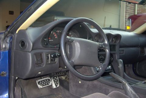 1994 Dodge Stealth - The interior of a 1994 Dodge Stealth features a dark dashboard, steering wheel, and sporty pedals.