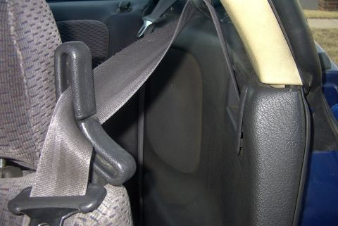 1994 Dodge Stealth - Close-up of a vehicle's interior, focusing on the seatbelt mechanism and adjacent trim.
