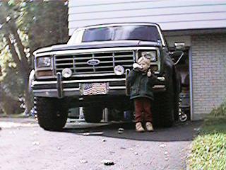 1986 Ford Bronco - Front view of a 1980s Ford Bronco, a child stands beside the vehicle.