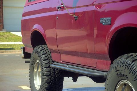 1994 Ford Bronco - Side view of a red 1994 Ford Bronco XL with aftermarket wheels and tires.