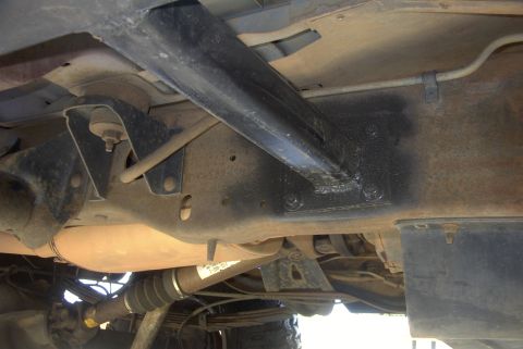 1994 Ford Bronco - The underside of a vehicle reveals its frame and mechanical parts, with a visible label on the driveshaft.