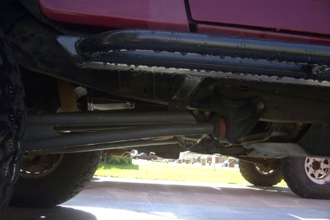 1994 Ford Bronco - Close-up of vehicle underbody, focusing on sliders and suspension parts. Includes website text.