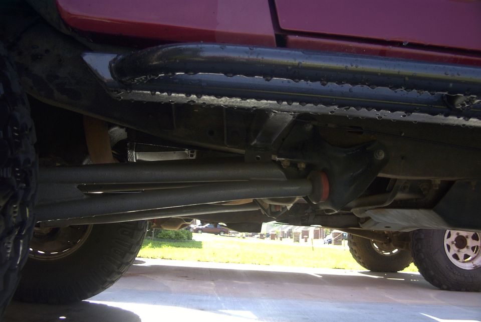 Underbody view of a vehicle showing sliders and suspension components. Text overlay reads SUPERMOTORS