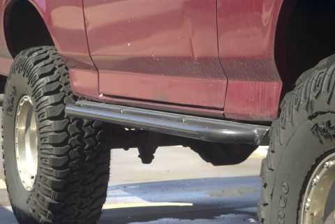 1994 Ford Bronco - Close-up of a 1994 Ford Bronco's side, highlighting its rock sliders and off-road tires.