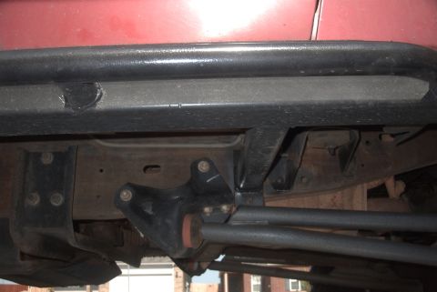 1994 Ford Bronco - Undercarriage view of a red vehicle, highlighting the black rock sliders and suspension components.