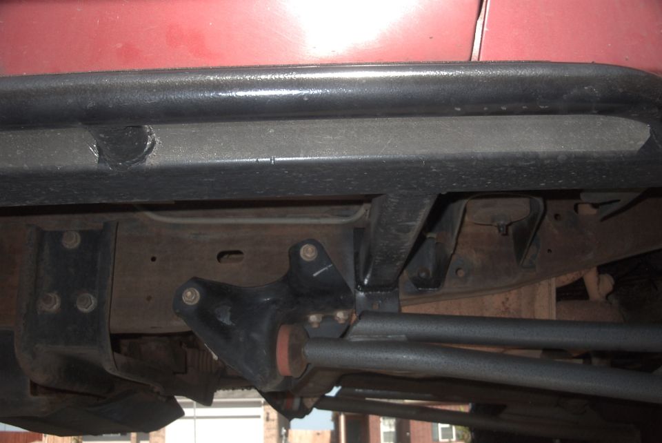 Red vehicle with black rock sliders and undercarriage detail