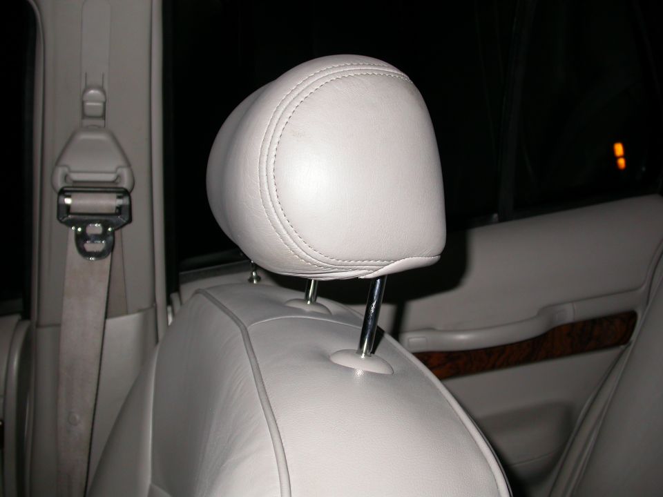 Light-colored leather headrest and seatbelt in a car interior