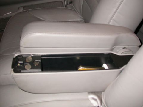 1998 Mercury Grand Marquis - The interior of a car shows an open armrest compartment with coins and a pen.