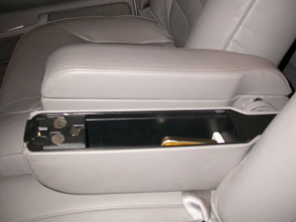 Car's center console armrest is open, showing coins and a pen inside