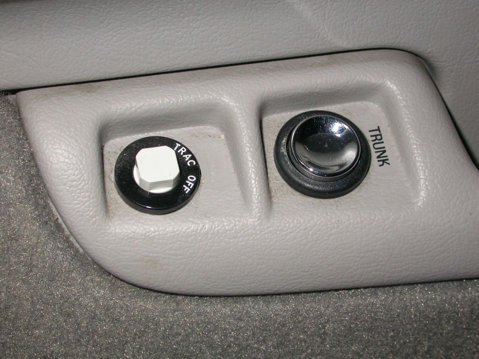 Close-up of a "TRAC OFF" button and a "TRUNK" release button inside a car