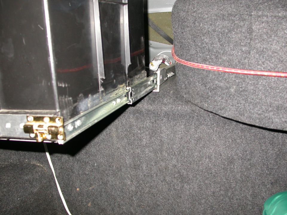 Close-up of a trunk drawer slide mechanism with a black drawer box and gray carpeted side panel