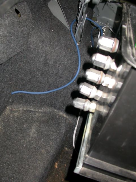 1998 Mercury Grand Marquis - Close-up view of wiring and lug nuts inside a car's trunk compartment.