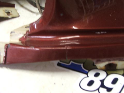 1965 Ford Mustang - Close-up of a damaged red car rocker panel with a Supermotors.net sticker visible.