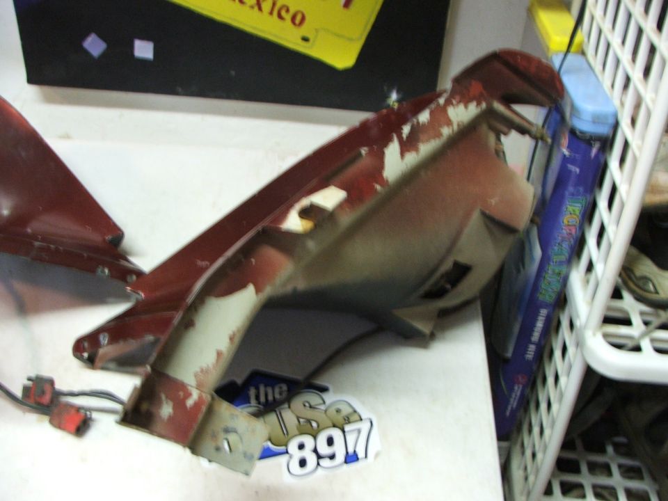 Red car part with peeling paint and visible wiring connectors
