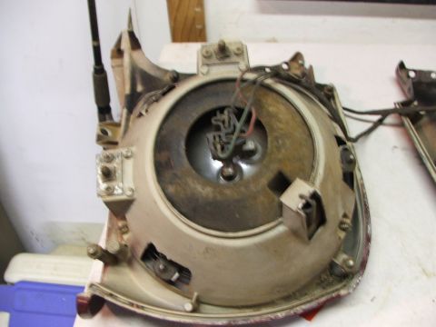 1965 Ford Mustang - Rear view of a 1965 Ford Mustang headlight assembly, showing wiring and mounting points.