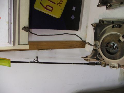 1965 Ford Mustang - A car headlight assembly and a fishing rod are visible in this image, with a yellow license plate in the background.