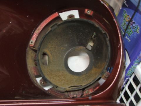 1965 Ford Mustang - Close-up of a 1965 Ford Mustang headlight bucket, showing the mounting points and interior rust.
