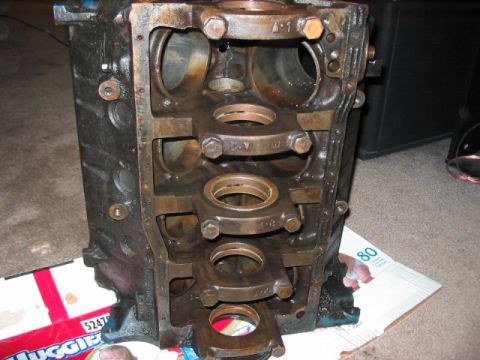 1991 Ford Bronco - Engine block with crankshaft bearing caps and bearings installed, resting on cardboard.