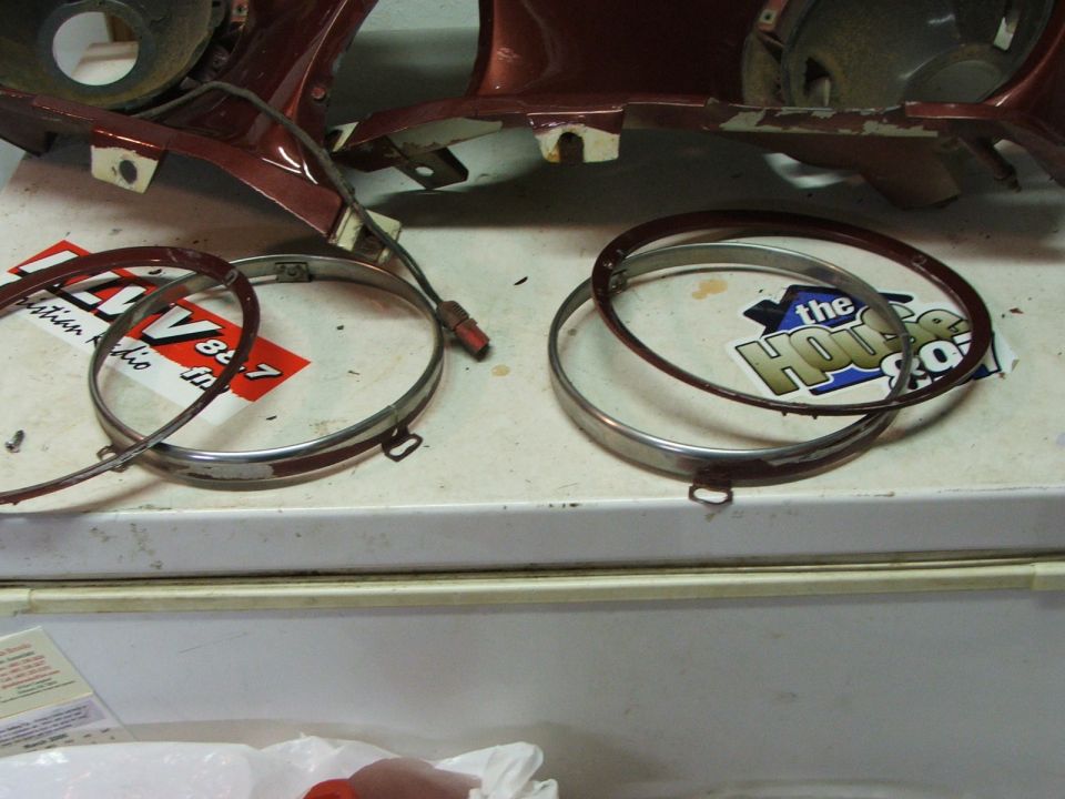 Two chrome headlight bezels and a piece of red car bodywork