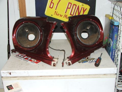 1965 Ford Mustang - Two red fender extensions, likely for a classic car, are displayed with a screwdriver nearby. A '67 PONY New Mexico license plate is visibl…