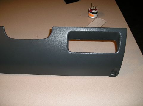 1993 Ford Bronco - A gray dashboard trim panel, likely for a vehicle's interior, is shown with a separate gauge placed nearby.