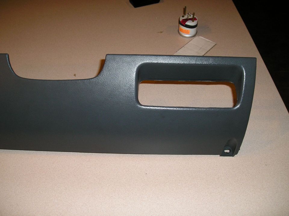 Gray dashboard trim panel with rectangular cutout and a small gauge