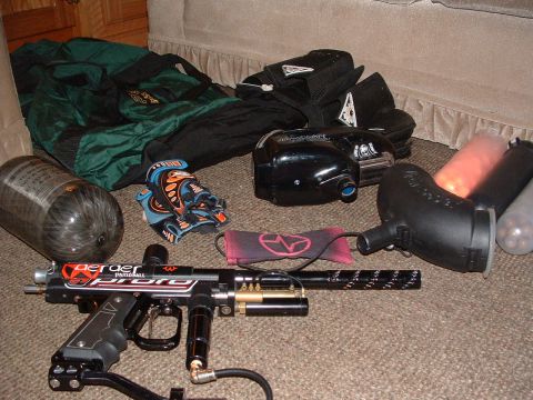 1984 Ford Bronco - Various pieces of paintball equipment, including a gun, air tank, mask, and pods, are laid out on a carpeted floor.