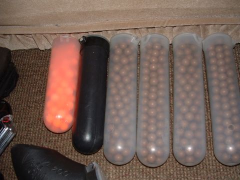 1984 Ford Bronco - Several paintball gun pods containing orange and brown paintballs are displayed on a carpeted surface.