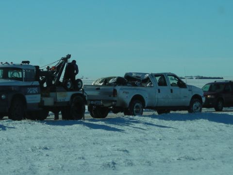 2002 Ford Excursion - A tow truck is hauling a pickup truck in a snowy landscape, with another vehicle following behind.