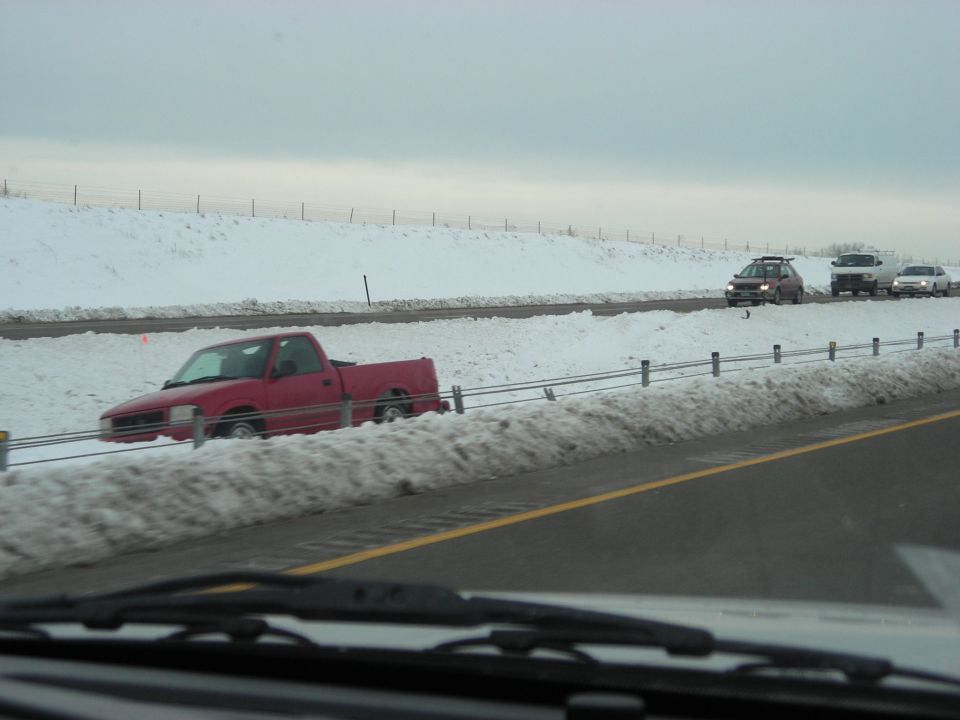 Red pickup truck stuck in snowy highway median with other vehicles across the road