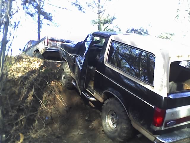 Black Ford Bronco on an off-road trail with open door on a hillside