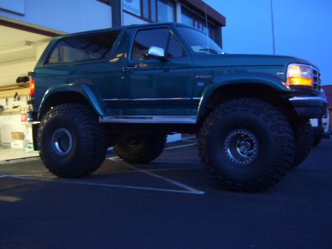 1996 Ford Bronco - A modified 1996 Ford Bronco is shown from a three-quarter front view under dim lighting.