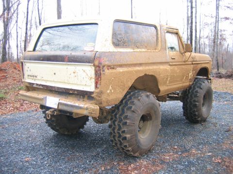 1992 Ford Mustang - This heavily modified 1978 Ford Bronco is covered in mud, parked on gravel.
