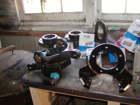 1991 Ford Bronco - Several black Spicer suspension components are laid out on a workbench, with boxes and a spray can visible in the background.