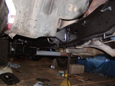 1991 Ford Bronco - Vehicle frame and suspension components are visible from underneath, supported by jack stands.