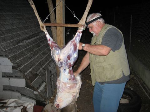 1986 Ford Bronco - A man is shown butchering a deer carcass outdoors at night, illuminated by a headlamp.