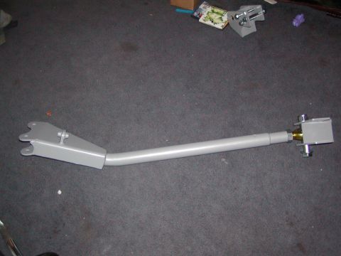 1991 Ford Bronco - Gray suspension control arm with bracket and bolts on carpeted floor.