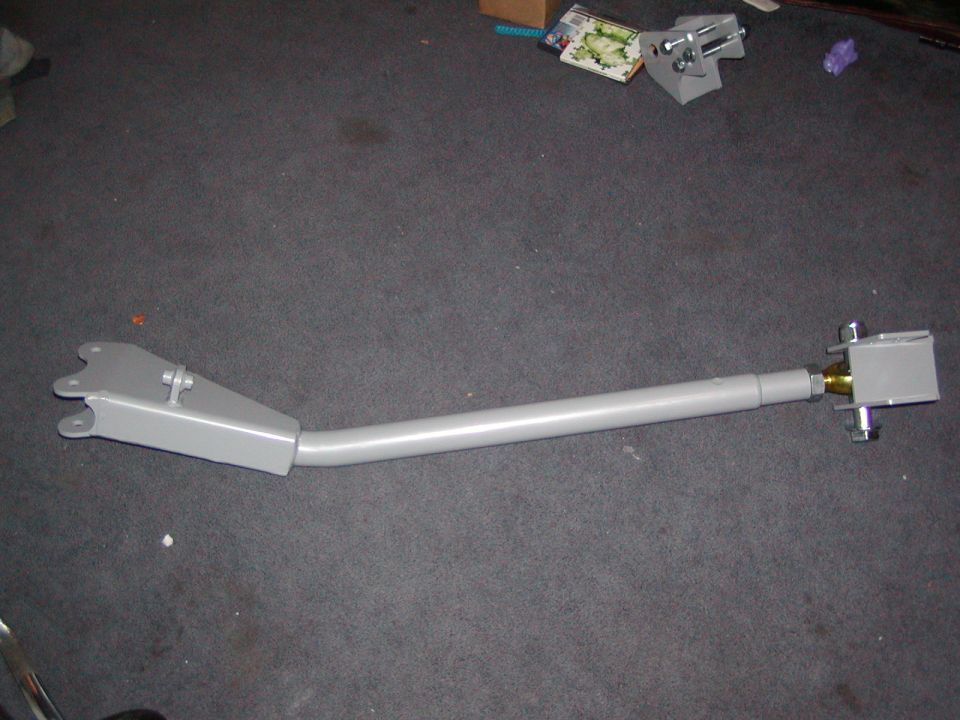 Gray suspension control arm with bracket and bolts on carpeted floor