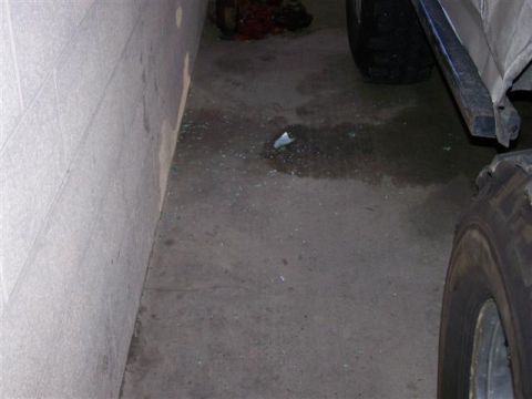 1995 Ford Bronco - A close-up view of a vehicle's tire and lower body panel, with scattered debris on the concrete floor.