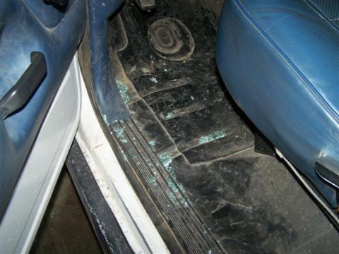 1995 Ford Bronco - The interior of a vehicle shows evidence of vandalism with shattered glass scattered on the floor.