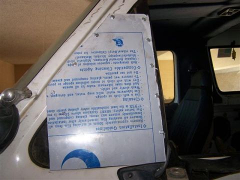 1995 Ford Bronco - A metal plate with installation and cleaning guidelines is attached to the interior door frame of a vehicle.