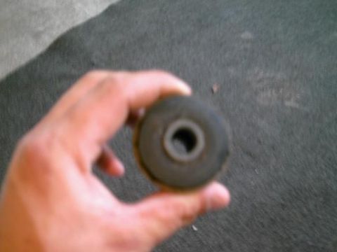 1986 Ford Bronco - A hand holds a rubber bushing, likely a suspension component.
