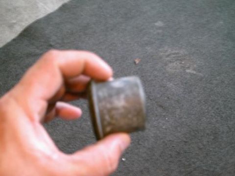 1986 Ford Bronco - A person holds a metal part, possibly a bushing or spacer, for inspection.