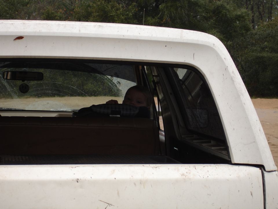 Child peeking over the seat in a white pickup truck bed