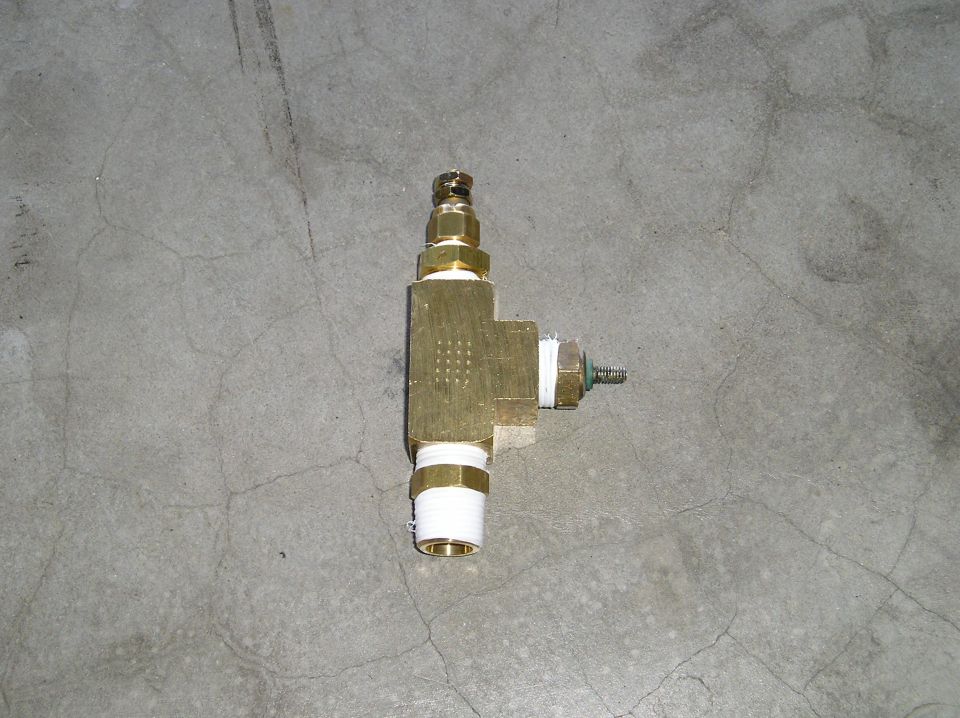 Brass tee fitting with PTFE tape on threaded ports, on concrete floor