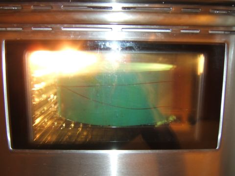 1980 Jeep CJ5 - A green object is being heated inside an oven, with bright light reflecting off the glass.