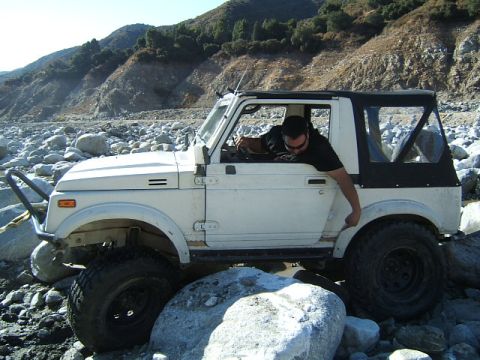 1988 Ford Bronco - A man drives a white off-road vehicle through a rocky, mountainous landscape.